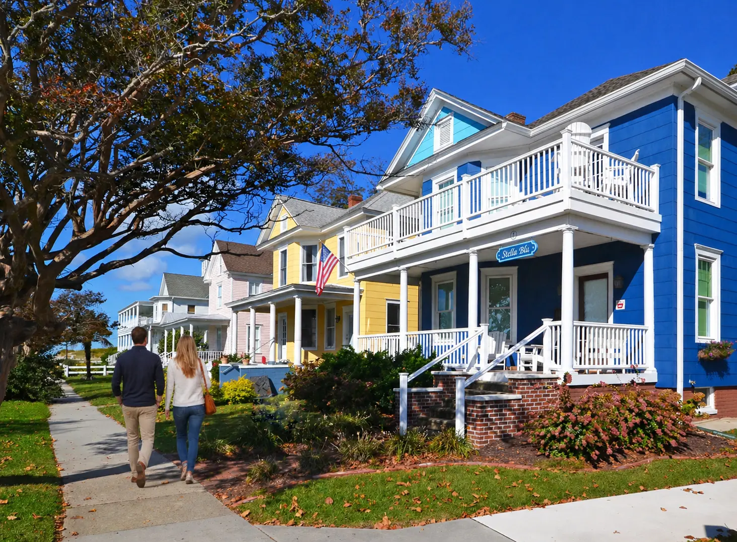 Couple walking past colorful Victorian homes in the Cape Charles historic district on a sunny fall day