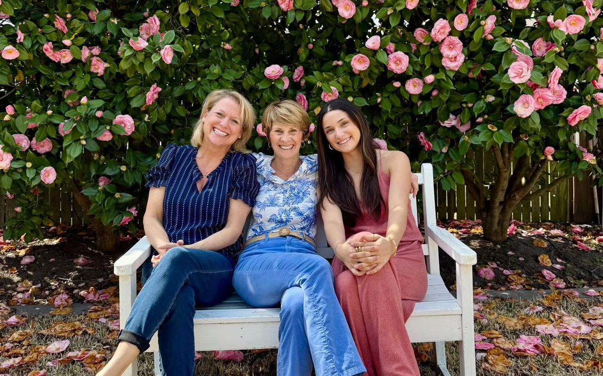 Chesapeake Properties real estate agents sitting together on a bench in front of a blooming camellia tree in Cape Charles, Virginia
