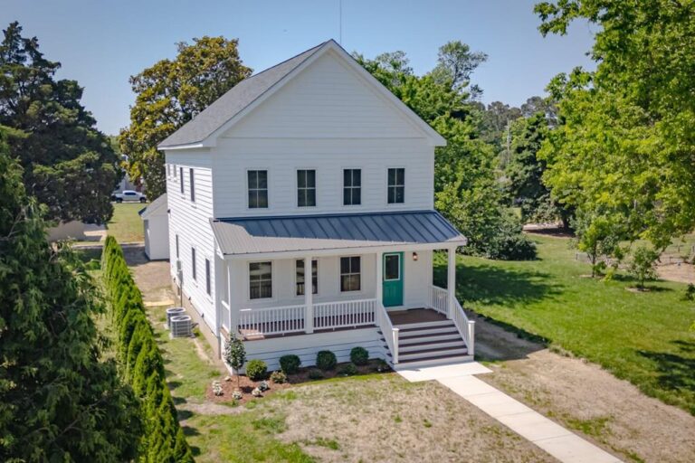 New white two-story farmhouse with a covered front porch in Cape Charles, illustrating the cost of living in Cape Charles for homebuyers
